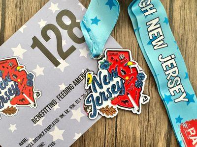 Virtualrunevent Race Through America 50 State Challenge medals and bibs displayed in a row on a white background.