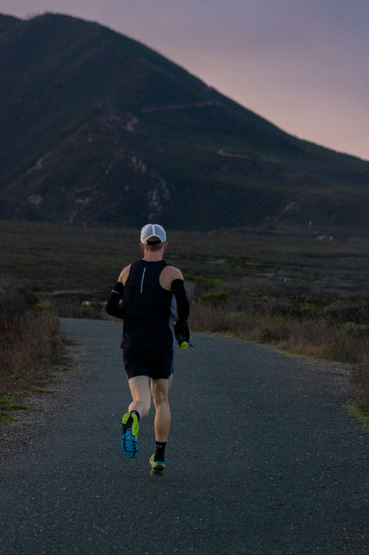 woman jogging on gray road across mountain during daytime