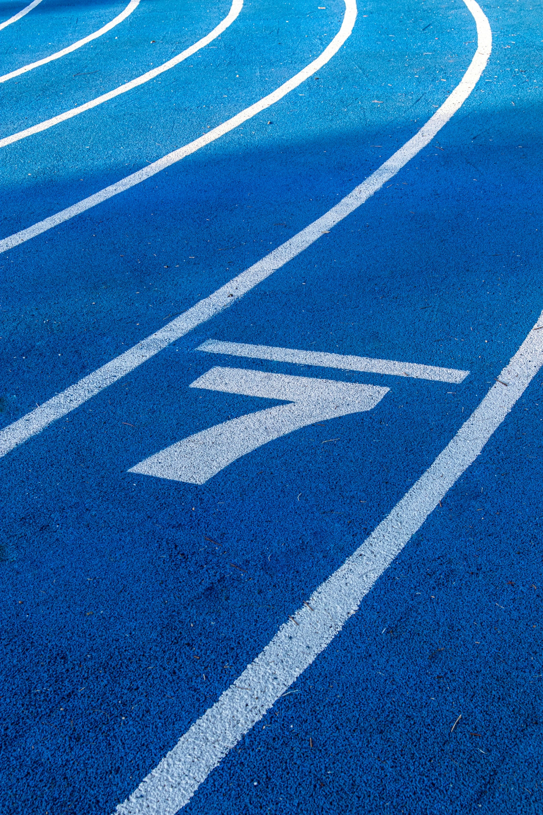A blue running track with white lane markings and a large number seven