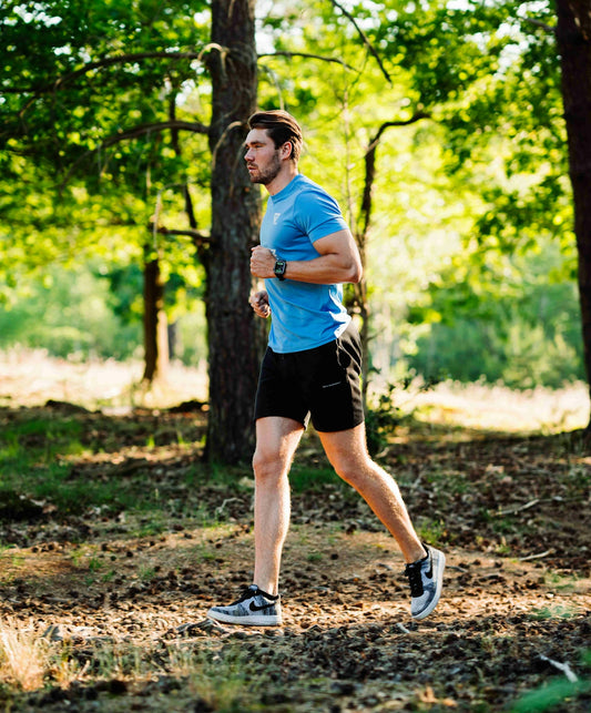 A man running through the woods in a blue shirt