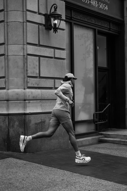 A man running down a street next to a tall building